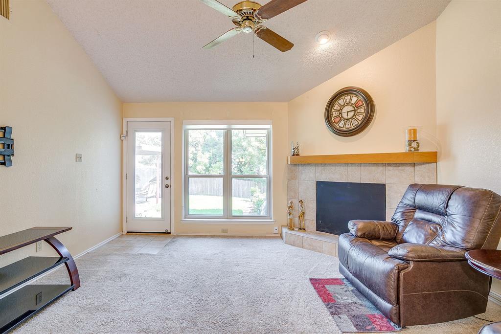 1116 Highpoint Road Bedford, TX 76022 - Photo 8 of 37 Living area featuring a textured ceiling, carpet floors, a tiled fireplace, a ceiling fan, and vaulted ceiling