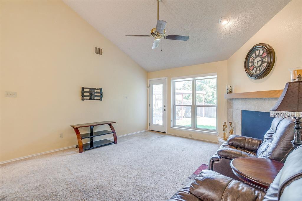 1116 Highpoint Road Bedford, TX 76022 - Photo 9 of 37 Living room with a textured ceiling, carpet flooring, a ceiling fan, a tiled fireplace, and high vaulted ceiling