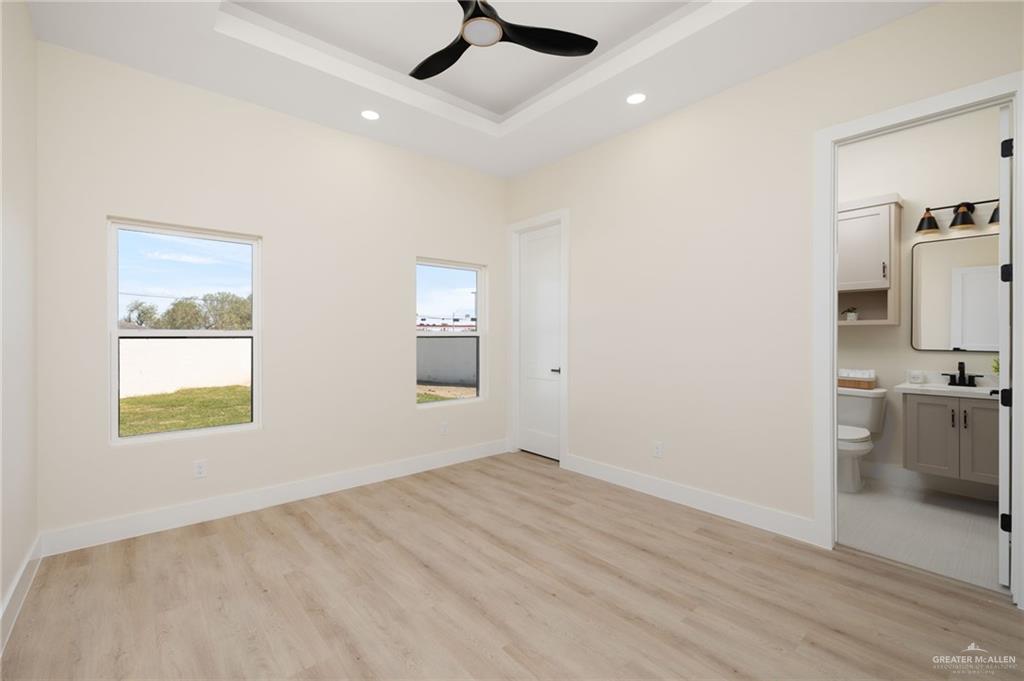 7820 North 38th Street McAllen, TX 78504 - Photo 22 of 31 Unfurnished bedroom featuring light wood-style flooring, a ceiling fan, ensuite bath, a tray ceiling, and recessed lighting