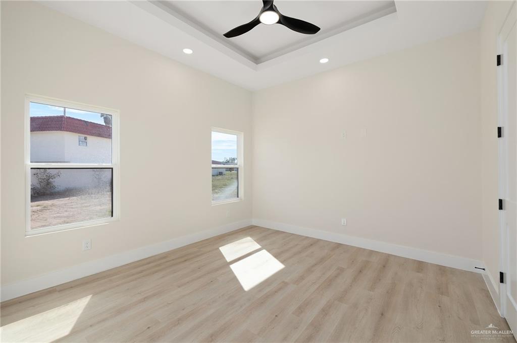 7820 North 38th Street McAllen, TX 78504 - Photo 24 of 31 Spare room with light wood-style floors, ceiling fan, a tray ceiling, and recessed lighting