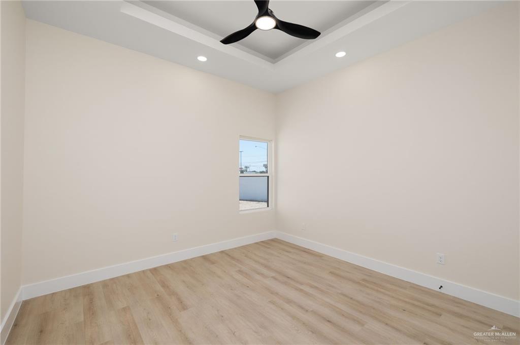 7820 North 38th Street McAllen, TX 78504 - Photo 27 of 31 Empty room with light wood-style flooring, a tray ceiling, recessed lighting, and a ceiling fan