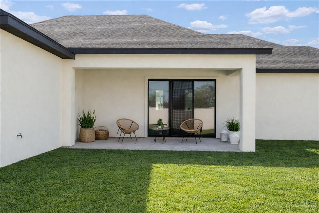 7820 North 38th Street McAllen, TX 78504 - Photo 30 of 31 Rear view of property featuring a yard, stucco siding, a shingled roof, and a patio area