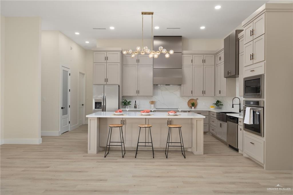 7820 North 38th Street McAllen, TX 78504 - Photo 4 of 31 Kitchen with a kitchen bar, hanging light fixtures, stainless steel appliances, a center island, and light wood-style flooring