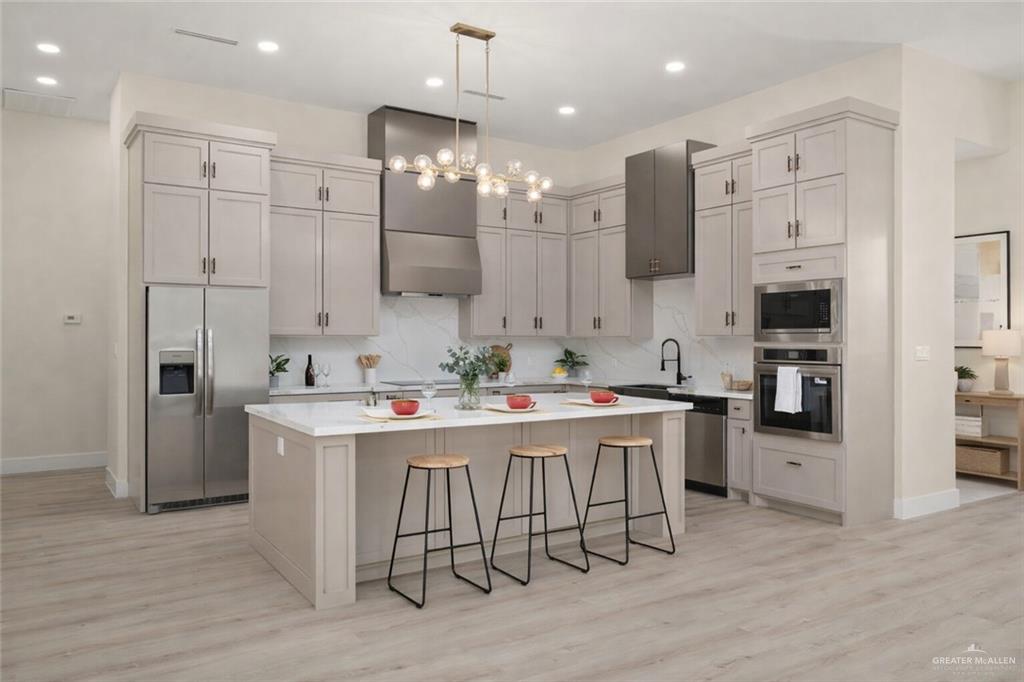 7820 North 38th Street McAllen, TX 78504 - Photo 5 of 31 Kitchen featuring a kitchen breakfast bar, appliances with stainless steel finishes, decorative light fixtures, a kitchen island, and light wood-style floors