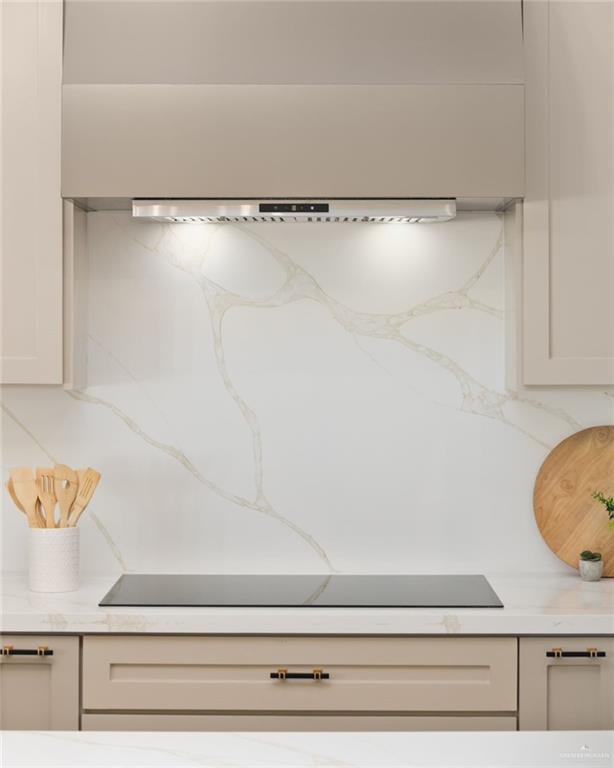 7820 North 38th Street McAllen, TX 78504 - Photo 9 of 31 Kitchen view of range hood, decorative backsplash, light stone countertops, black electric cooktop, and cream cabinetry
