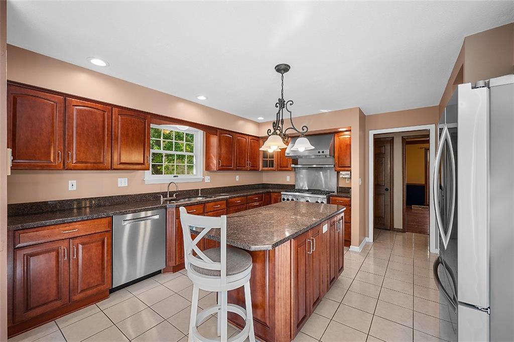 409 Bryn Court Pittsburgh, PA 15237 - Photo 13 of 50 a kitchen with stainless steel appliances granite countertop a stove a sink dishwasher and a refrigerator with wooden cabinets