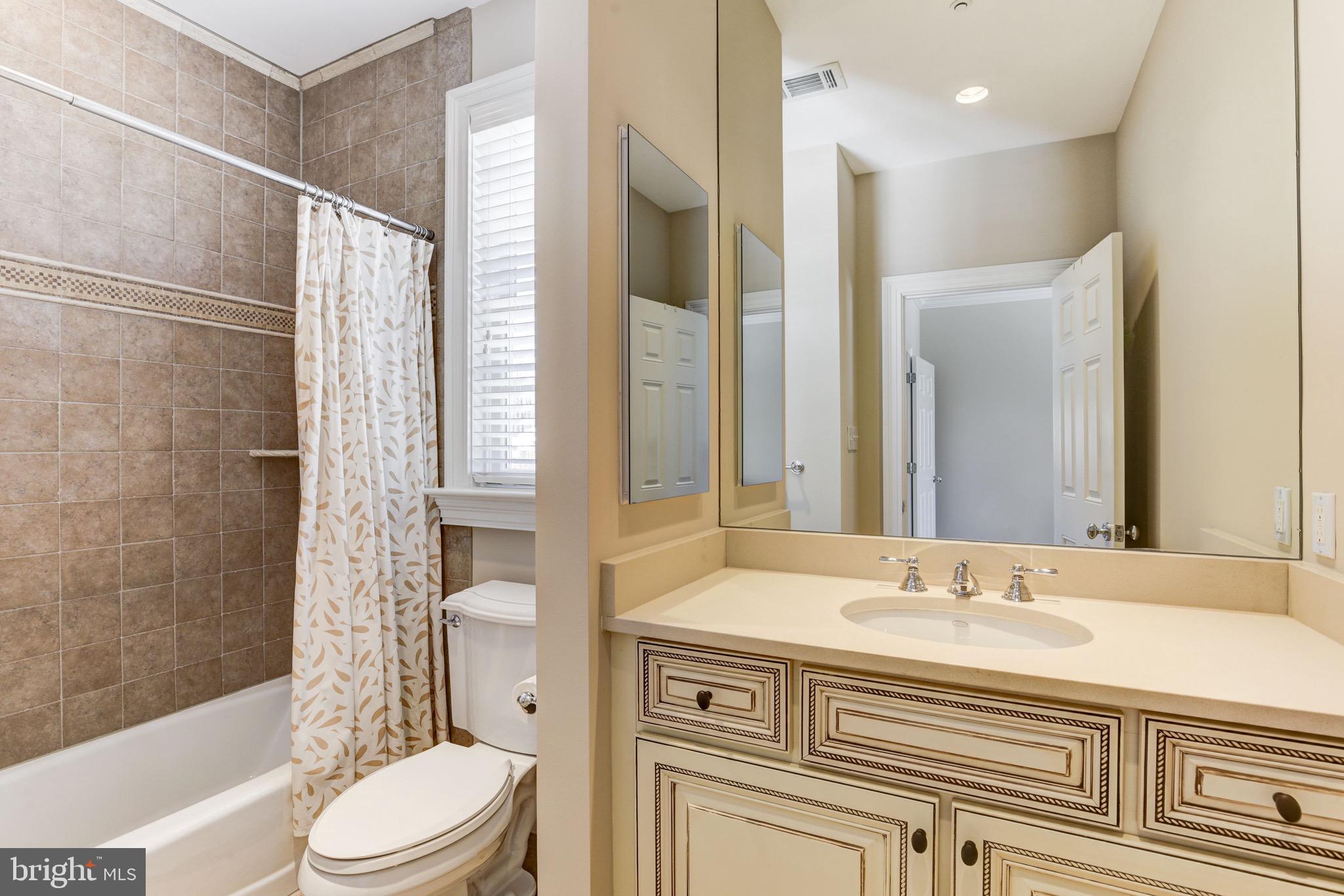 9809 Newhall Road Potomac, MD 20854 - Photo 22 of 37 a bathroom with a granite countertop sink toilet a mirror a bathtub and shower
