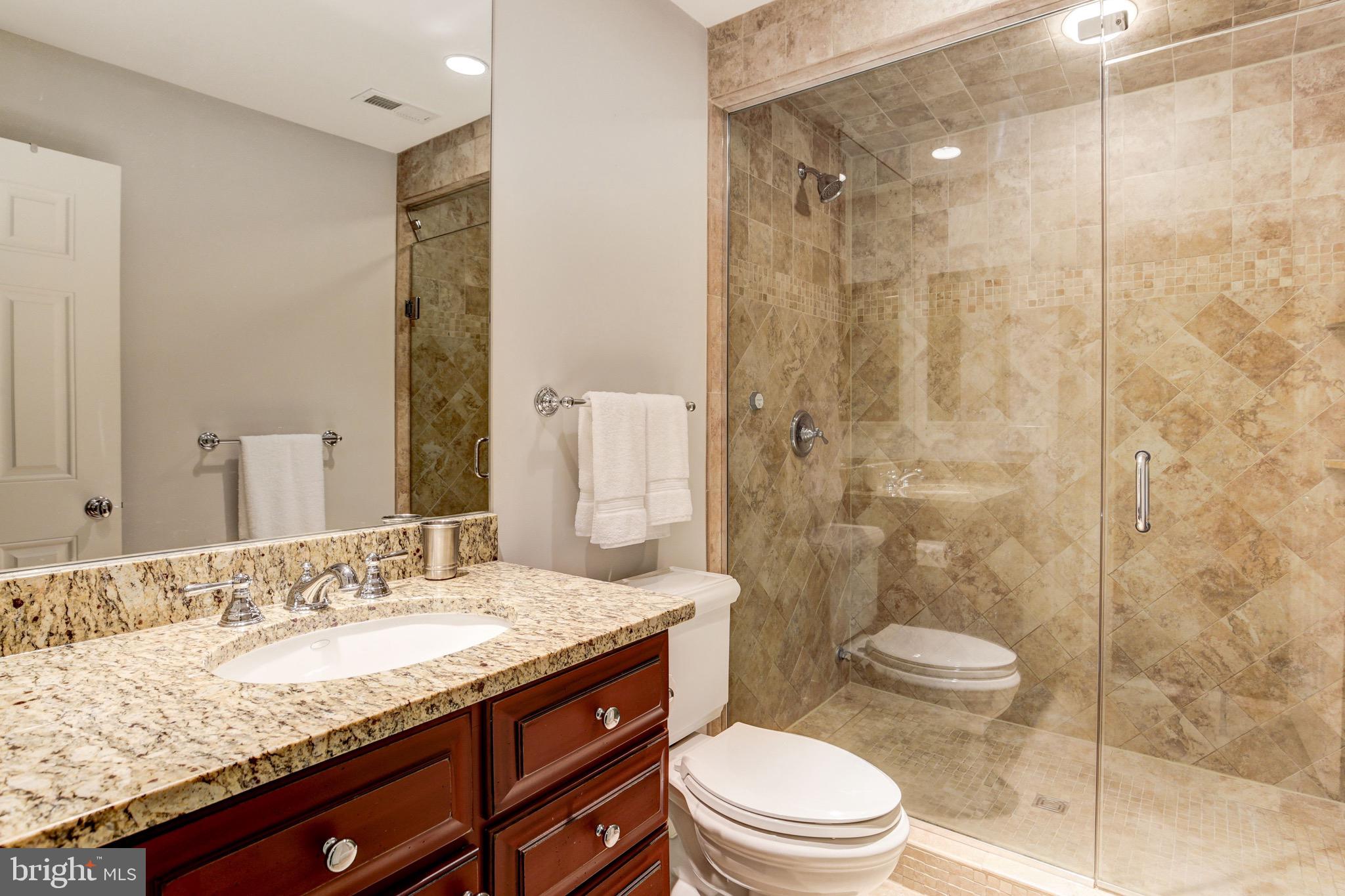 9809 Newhall Road Potomac, MD 20854 - Photo 35 of 37 a bathroom with a granite countertop sink a toilet a mirror and shower