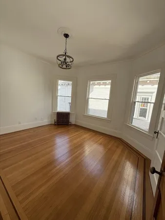 a view of an empty room with wooden floor and windows