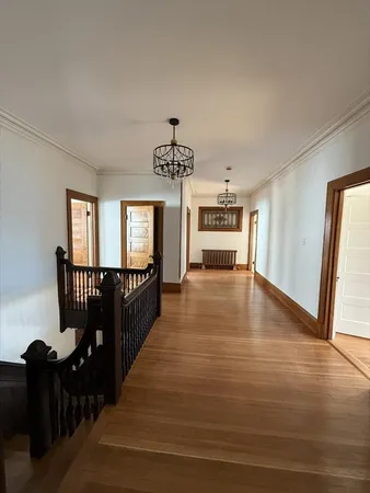 a view of a hallway with wooden floor and windows