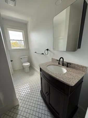 a bathroom with a granite countertop sink a toilet and a mirror