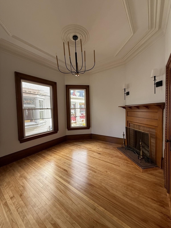72 Belmont Street, Unit 1 Fall River, MA 02720 - Photo 8 of 20 an empty room with wooden floor fireplace and windows
