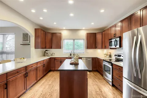 a large kitchen with granite countertop a large counter top stainless steel appliances a sink cabinets and a window