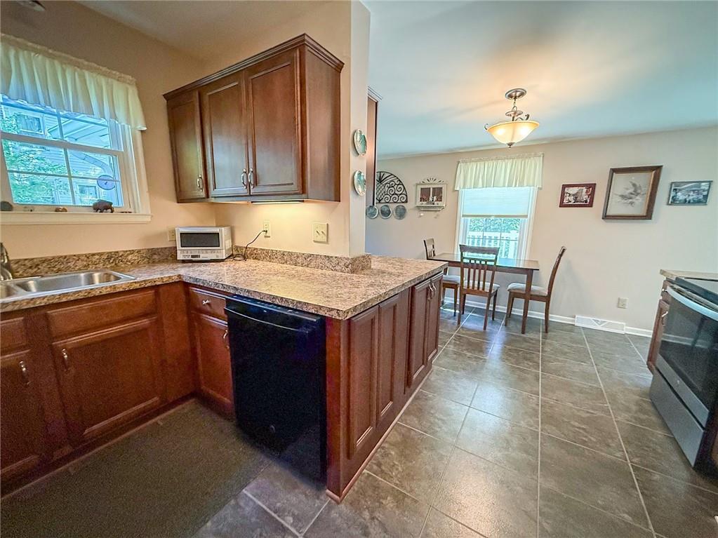 306 Beechwood Boulevard Butler, PA 16001 - Photo 14 of 40 a kitchen with a stove a sink a microwave and wooden cabinets