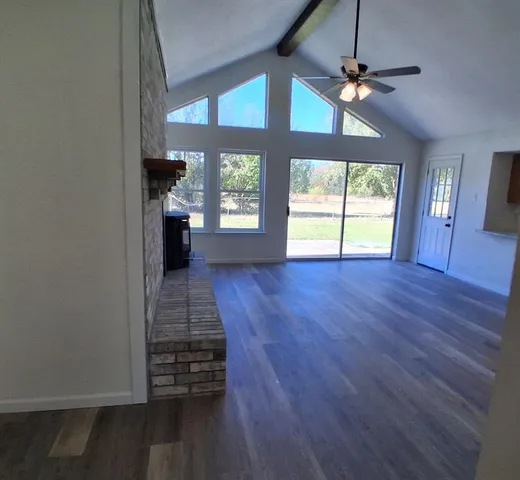 an empty room with wooden floor fan and windows