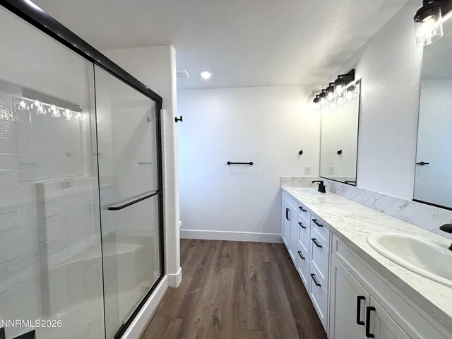 a bathroom with a double vanity sink a mirror and a shower