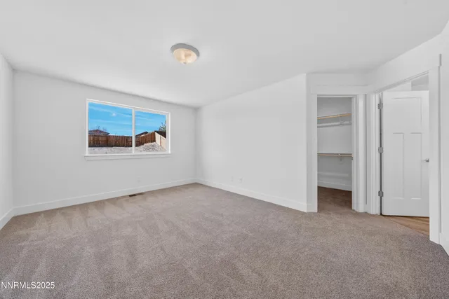 a view of an empty room with closet and a window