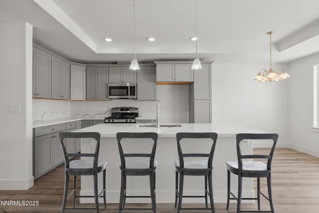 a kitchen with stainless steel appliances granite countertop a table chairs refrigerator and microwave