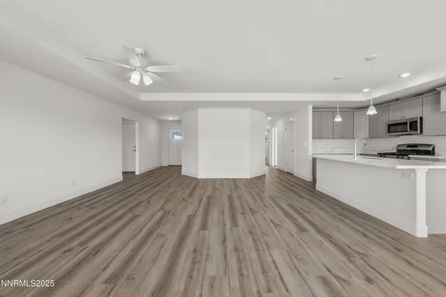 a view of empty room with wooden floor and ceiling fan