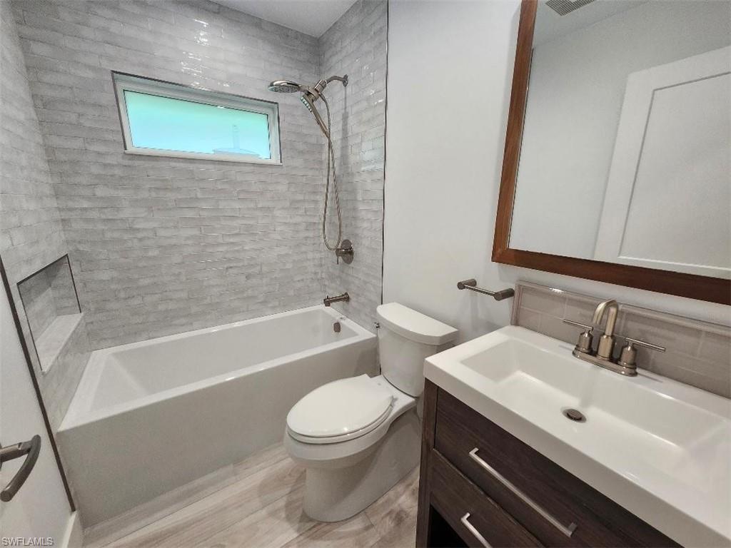 512 Raven Way Naples, FL 34110 - Photo 15 of 20 Bathroom featuring shower / bathtub combination, vanity, and wood finished floors