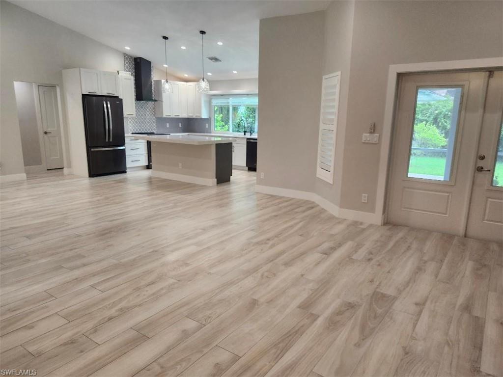 512 Raven Way Naples, FL 34110 - Photo 20 of 20 Kitchen with open floor plan, black appliances, light countertops, wall chimney exhaust hood, and white cabinets