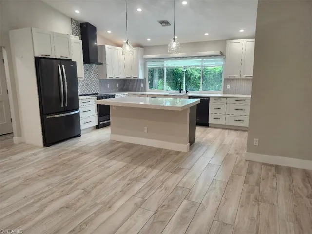 a view of a kitchen with stainless steel appliances kitchen island wooden floor and living room view