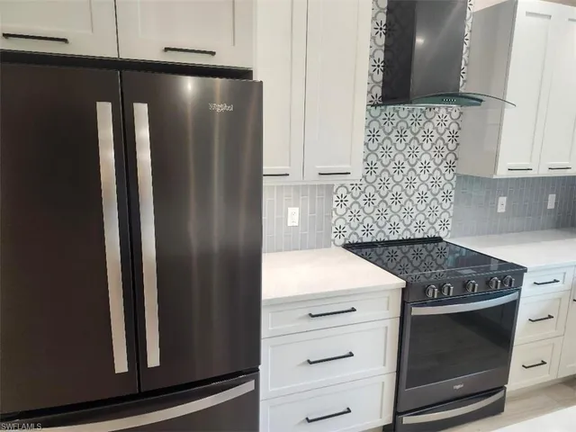 a large kitchen with kitchen island a stove a sink dishwasher and white cabinets with wooden floor