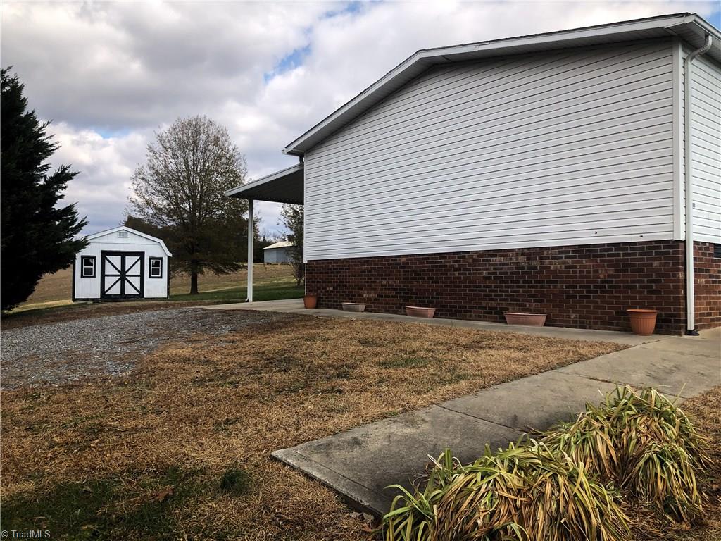 679 Mt Zion Road Pinnacle, NC 27043 - Photo 7 of 30 view of side of home, carport, storage building and sidewalks to front porch.