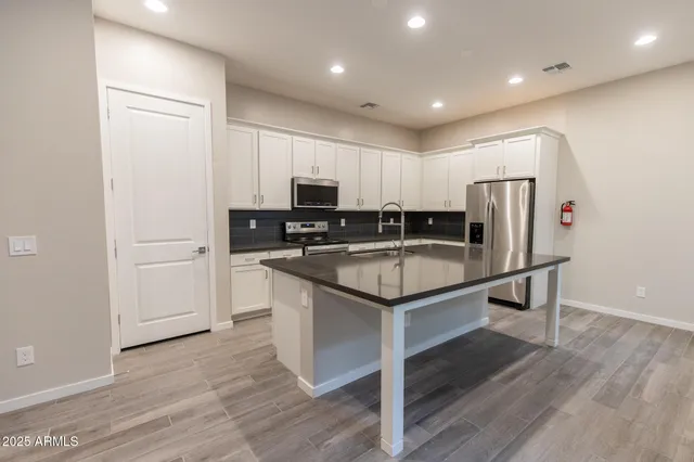 a kitchen with a refrigerator and white cabinets