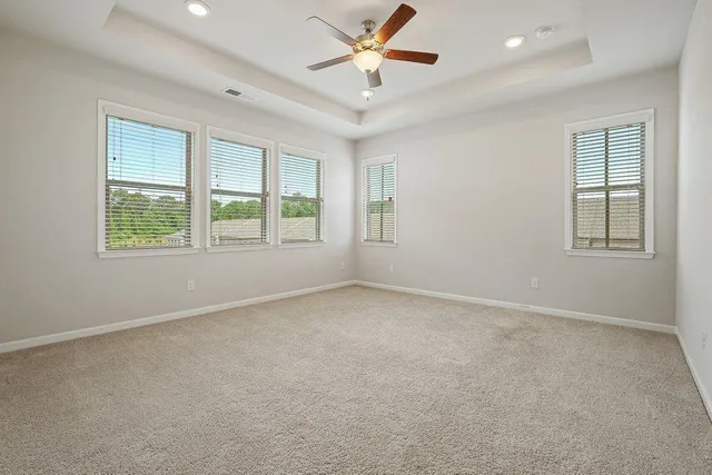 an empty room with chandelier fan and windows