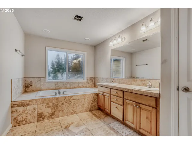 a spacious bathroom with a tub double sink and mirror