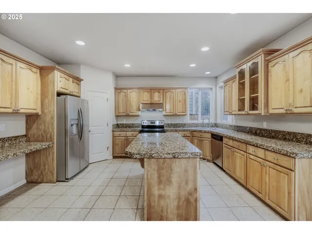 a large kitchen with granite countertop a large counter top stainless steel appliances and cabinets