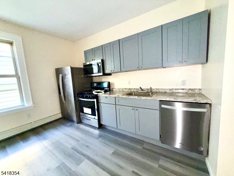 37-39 Field Place, Unit 2R Newark, NJ 07112 - Photo 5 of 10 a kitchen with granite countertop stainless steel appliances and wooden cabinets