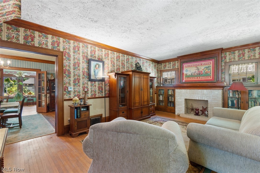 Living room featuring light hardwood / wood-style floors, a textured ceiling, crown molding, and plenty of natural light