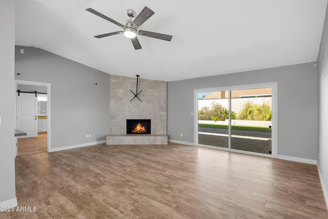 an empty room with fireplace fan and windows