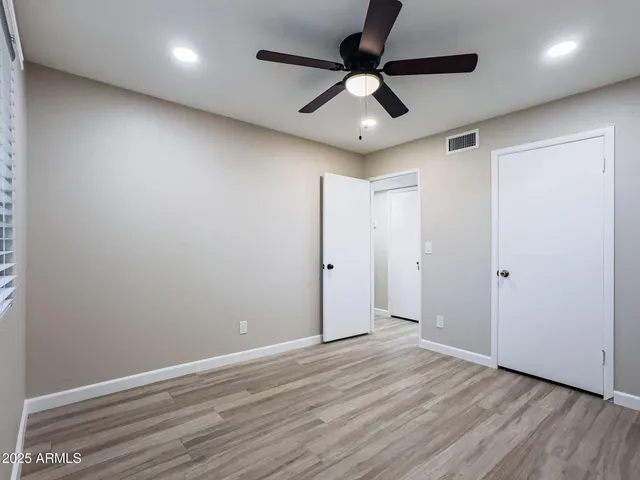 an empty room with wooden floor and ceiling fan