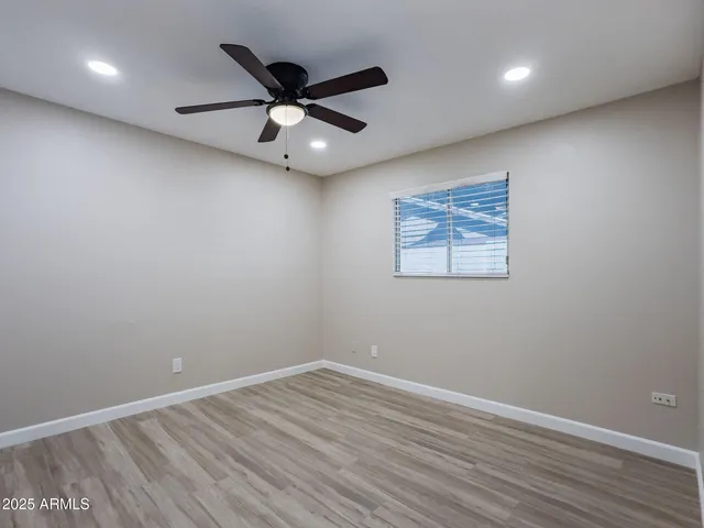an empty room with wooden floor fan and windows