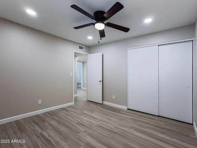an empty room with wooden floor and ceiling fan