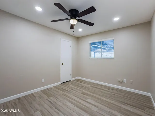 an empty room with wooden floor and ceiling fan