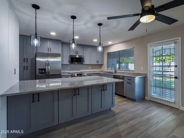 a kitchen with kitchen island granite countertop a sink stainless steel appliances and wooden floor
