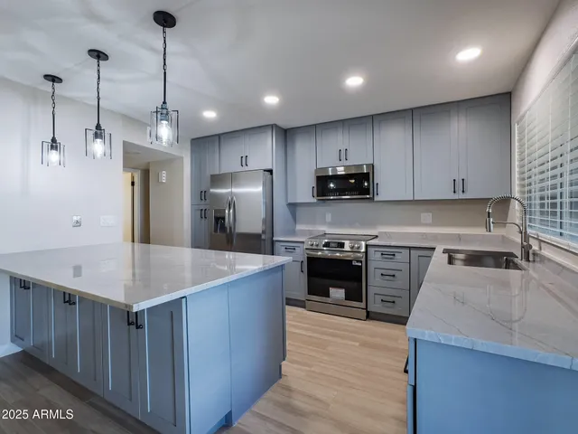 a large kitchen with stainless steel appliances granite countertop a stove a refrigerator a sink a oven and a center island