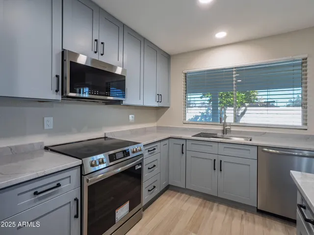 a kitchen with stainless steel appliances granite countertop a stove a sink and a microwave