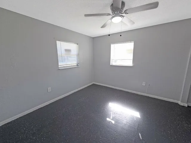 an empty room with a window and a fan