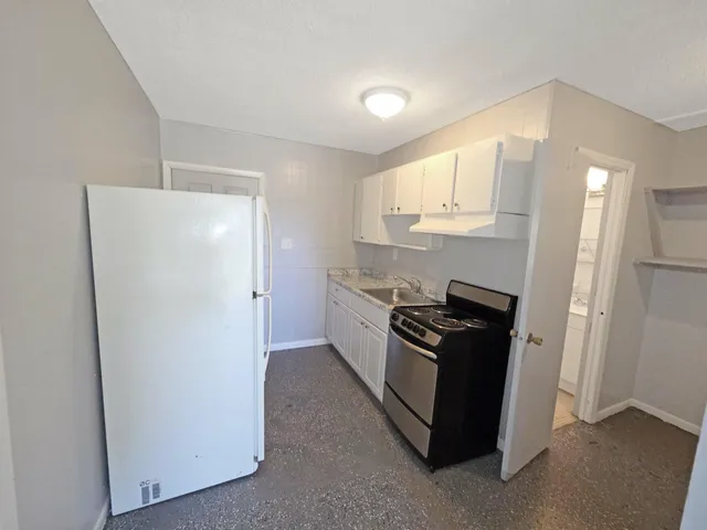 a kitchen with granite countertop white cabinets and stainless steel appliances