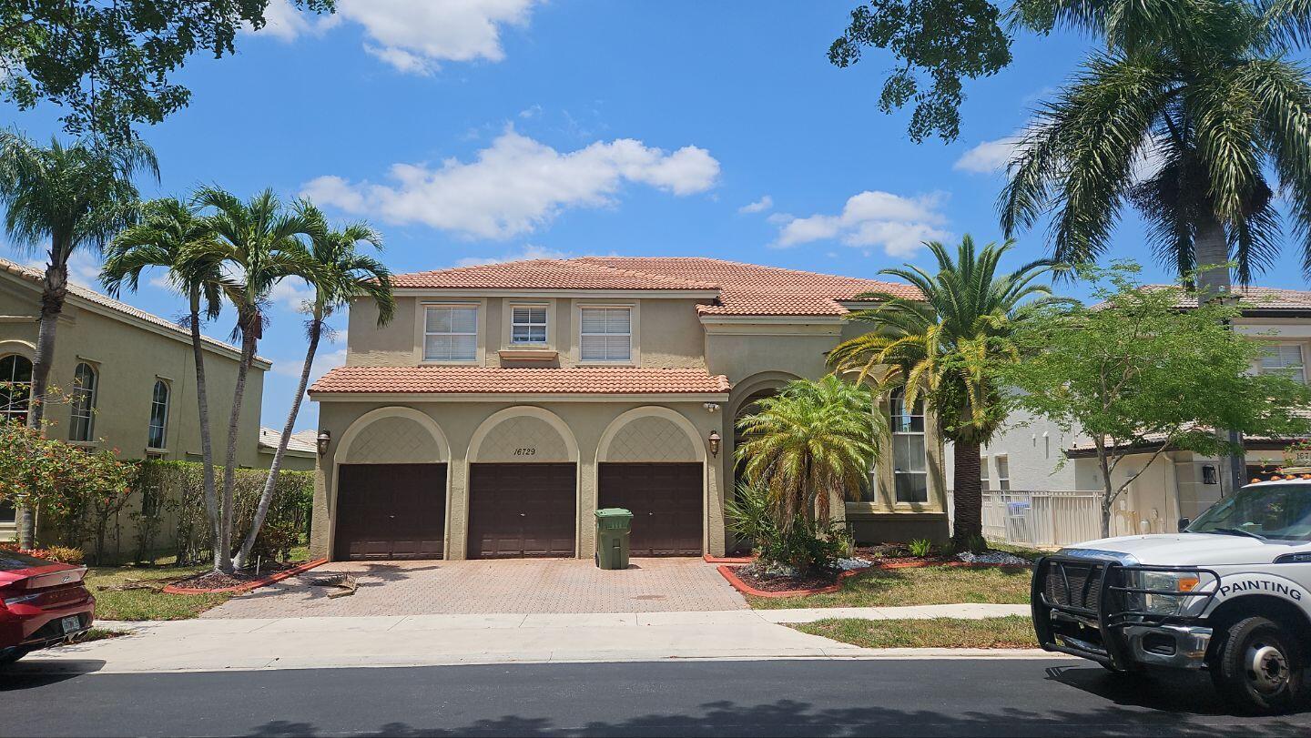 a view of a house with a yard and palm trees