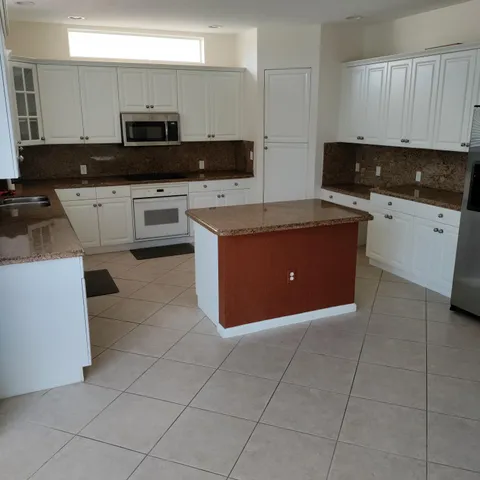 a kitchen with kitchen island granite countertop a stove top oven a sink a counter top space and cabinets