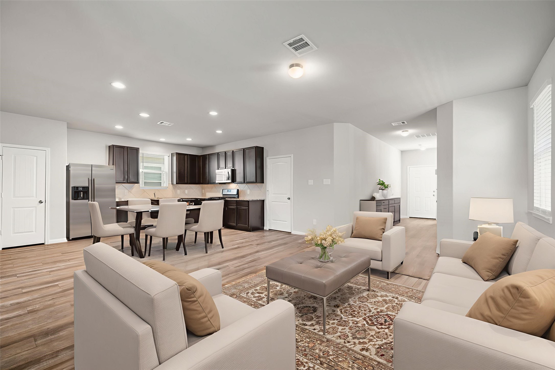 3571 Cannon Drive Conroe, TX 77301 - Photo 2 of 39 This photo showcases a spacious open-concept kitchen and living area with modern, dark wood cabinetry and stainless-steel appliances. The room features ample natural light and wood-style flooring, creating a warm and inviting atmosphere. *Virtually staged*