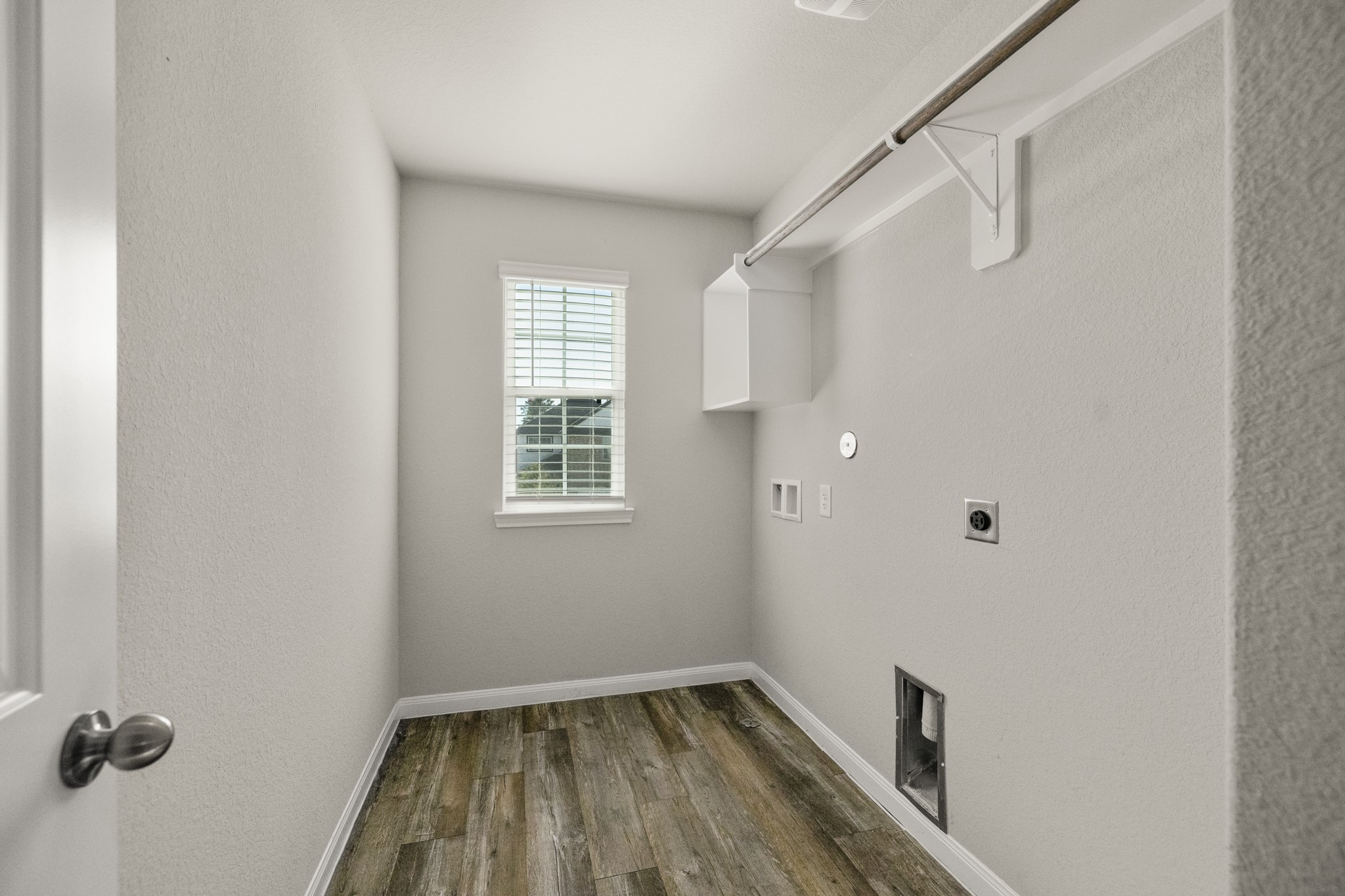 3571 Cannon Drive Conroe, TX 77301 - Photo 24 of 39 This photo shows a 2nd level laundry room with a single window providing natural light. It has hookups for a washer and dryer, a shelf for storage, and wood-style flooring.