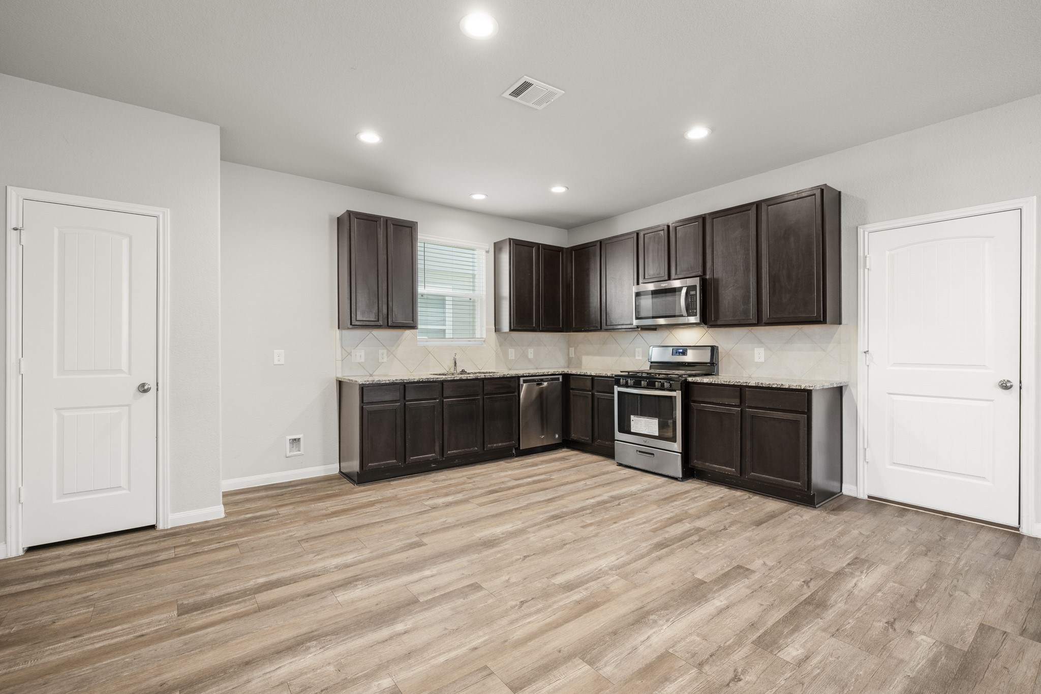 3571 Cannon Drive Conroe, TX 77301 - Photo 7 of 39 Bright, spacious kitchen with modern appliances, dark wood cabinets, and light wood flooring. Features ample counter space and a neutral color palette.