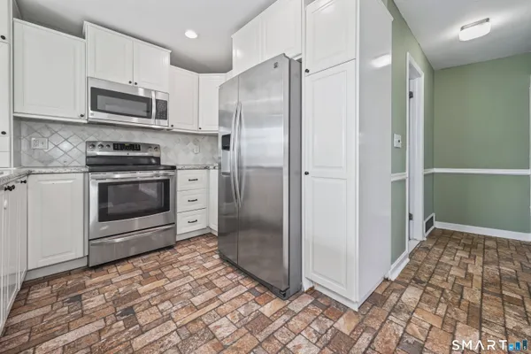 a kitchen with stainless steel appliances granite countertop a refrigerator and a stove top oven